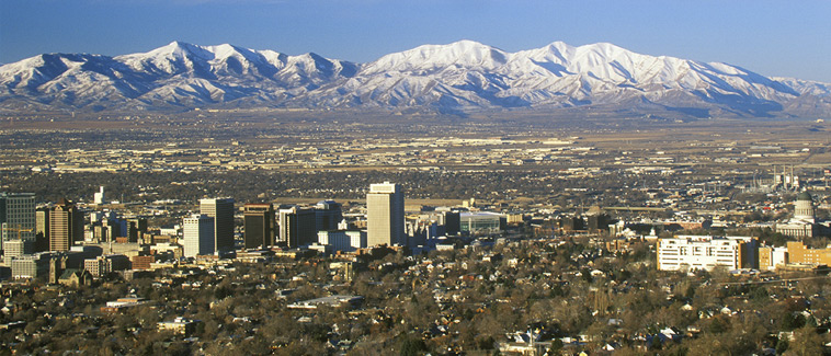 Skyline view of Salt Lake City, Utah with snow-covered Wasatch Mountains in the background.
